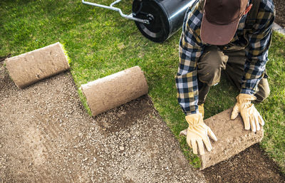 Mature man wearing cap fixing lawn outdoors