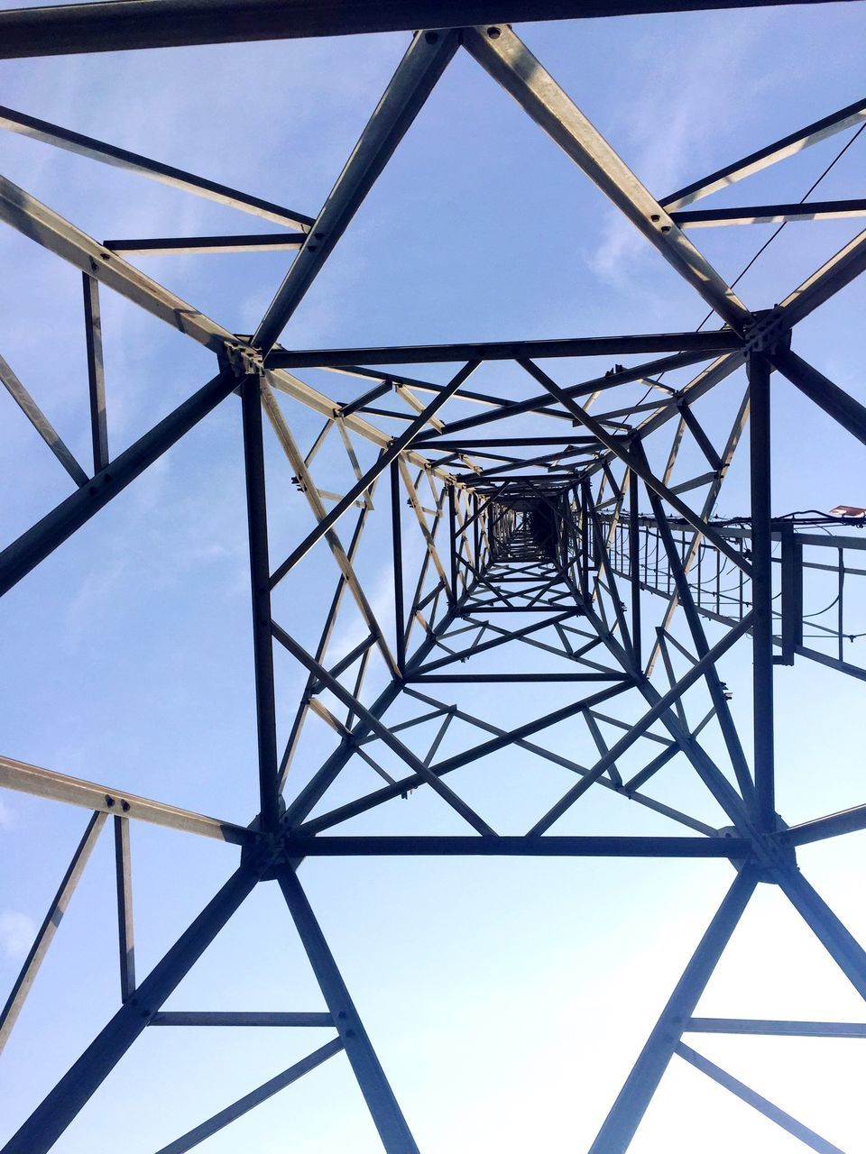 low angle view, connection, metal, clear sky, metallic, electricity pylon, built structure, sky, grid, power line, engineering, power supply, day, architecture, fuel and power generation, no people, outdoors, electricity, directly below, cable