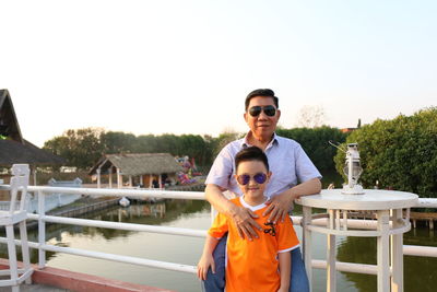 Portrait of young man wearing sunglasses standing against clear sky