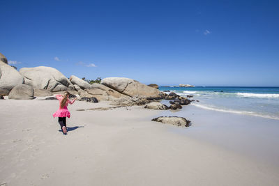 Rear view of teenage girl walking at beach