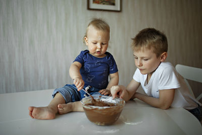 Cute sibling eating food at home