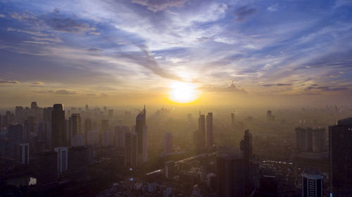 Modern buildings in city against sky during sunset