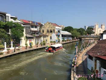 Canal amidst buildings in city against clear sky