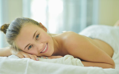 Portrait of smiling young woman lying on bed at home