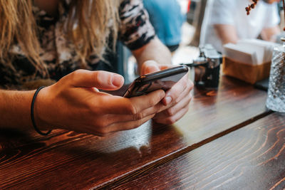 Midsection of woman using mobile phone on table