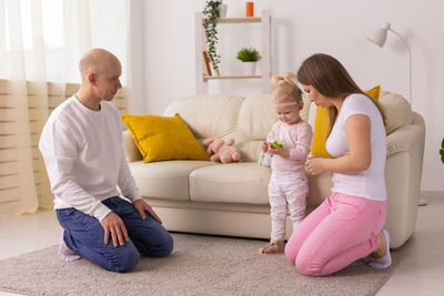 Side view of mother and daughter sitting on sofa at home