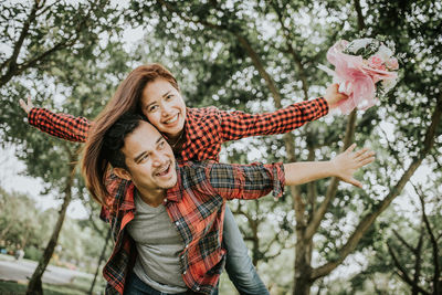 Portrait of smiling young woman holding flowers in park