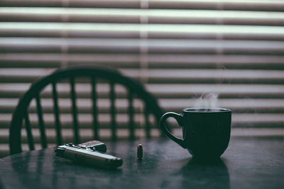 .45 handgun on dining room table alongside a steaming hot cup of coffee