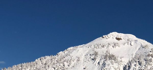 Low angle view of snow mountains against clear blue sky