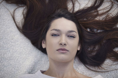 Close-up portrait of woman lying on bed at home