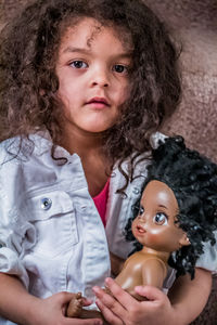 Portrait of cute girl with doll at home