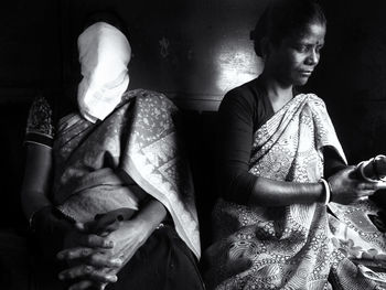 Woman wearing sari while sitting by wall