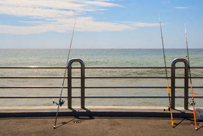 Empty railing by sea against sky