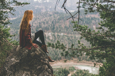 Side view of woman sitting on rock