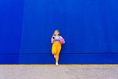 Full length of young woman standing against wall