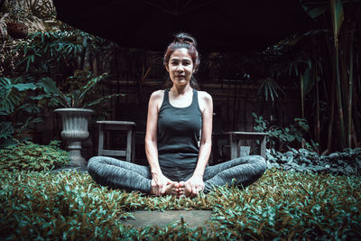 Portrait of woman doing yoga amidst plants