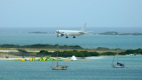 Airplane flying over sea against clear sky