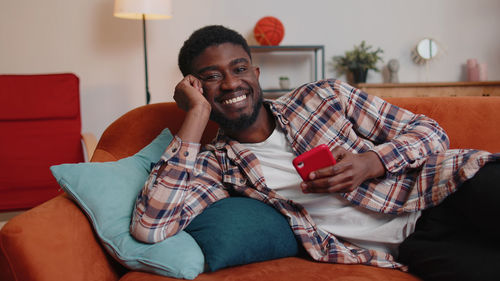 Portrait of smiling man using mobile phone on sofa