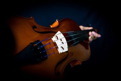 Close-up of man playing guitar against black background