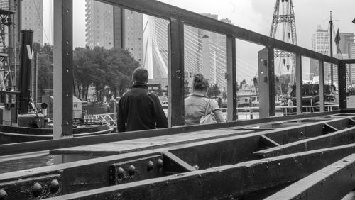 Rear view of people walking on bridge in city