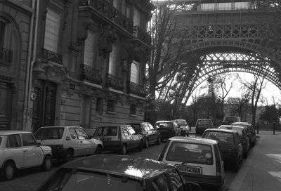 Cars parked on street by buildings against eiffel tower
