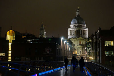 People in illuminated cathedral against sky at night