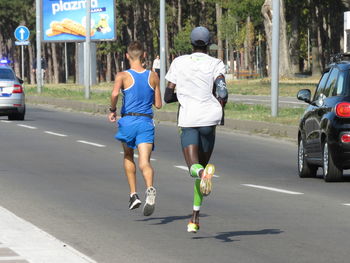 Rear view of people walking on road in city