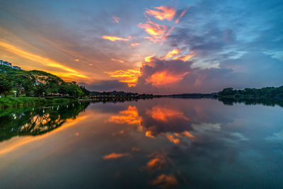 Scenic view of lake against dramatic sky during sunset