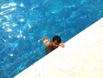 High angle portrait of smiling boy swimming in pool