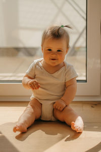 Portrait of smiling baby sitting against window