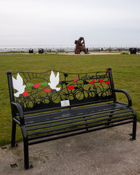 Empty bench in park against sky