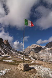 Low angle view of flag against mountain - dolomites mountains - locatelli refuge - italy