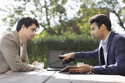 Businessman discussing with male colleague through laptop at outdoor cafe