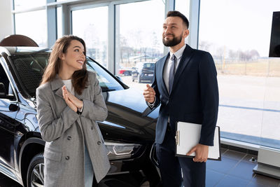 Smiling young man talking with car sales person