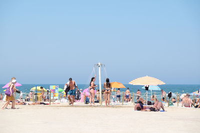 People on beach against clear sky