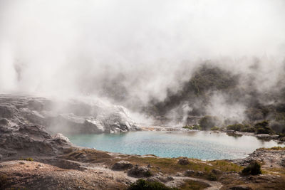 Scenic view of hot spring against cloudy sky