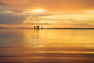 Silhouette women at beach against sky during sunset