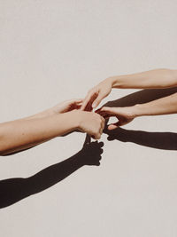 Cropped hands of women against gray wall