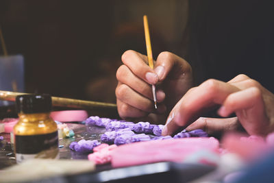 Cropped hands of person painting clay on table