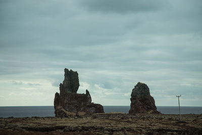 Rock formation by sea against sky