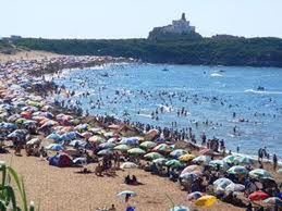 water, beach, sea, large group of people, clear sky, shore, built structure, building exterior, architecture, sand, day, stone - object, nature, abundance, sky, incidental people, outdoors, vacations