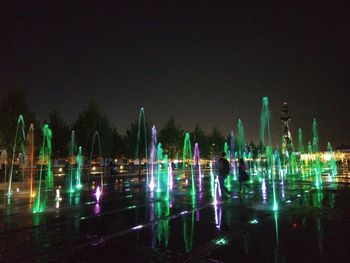 Illuminated fountain in city against clear sky at night