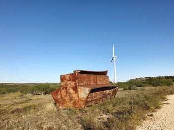 Traditional windmill on field against clear blue sky