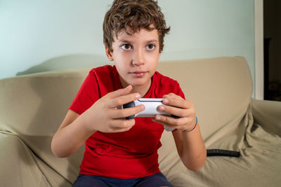 Little gamer boy playing video games sitting on the couch. kid using a consolle game controller