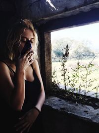 Midsection of woman sitting by window