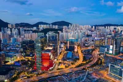 High angle view of illuminated street amidst buildings against sky