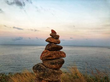 Stack of stones in sea against sky