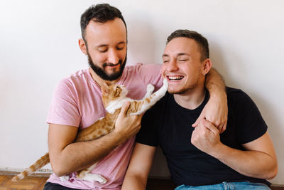 Gay couple playing with kitten.