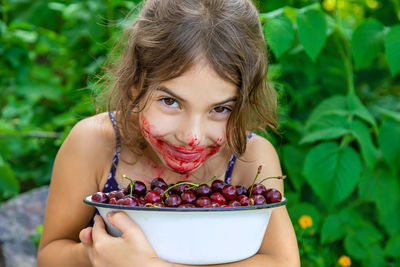 Portrait of smiling girl holding bowl of cherries
