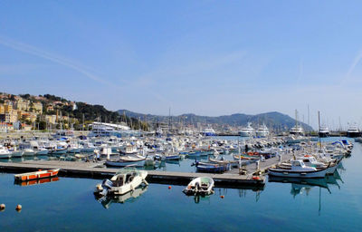 Boats moored at harbor against sky